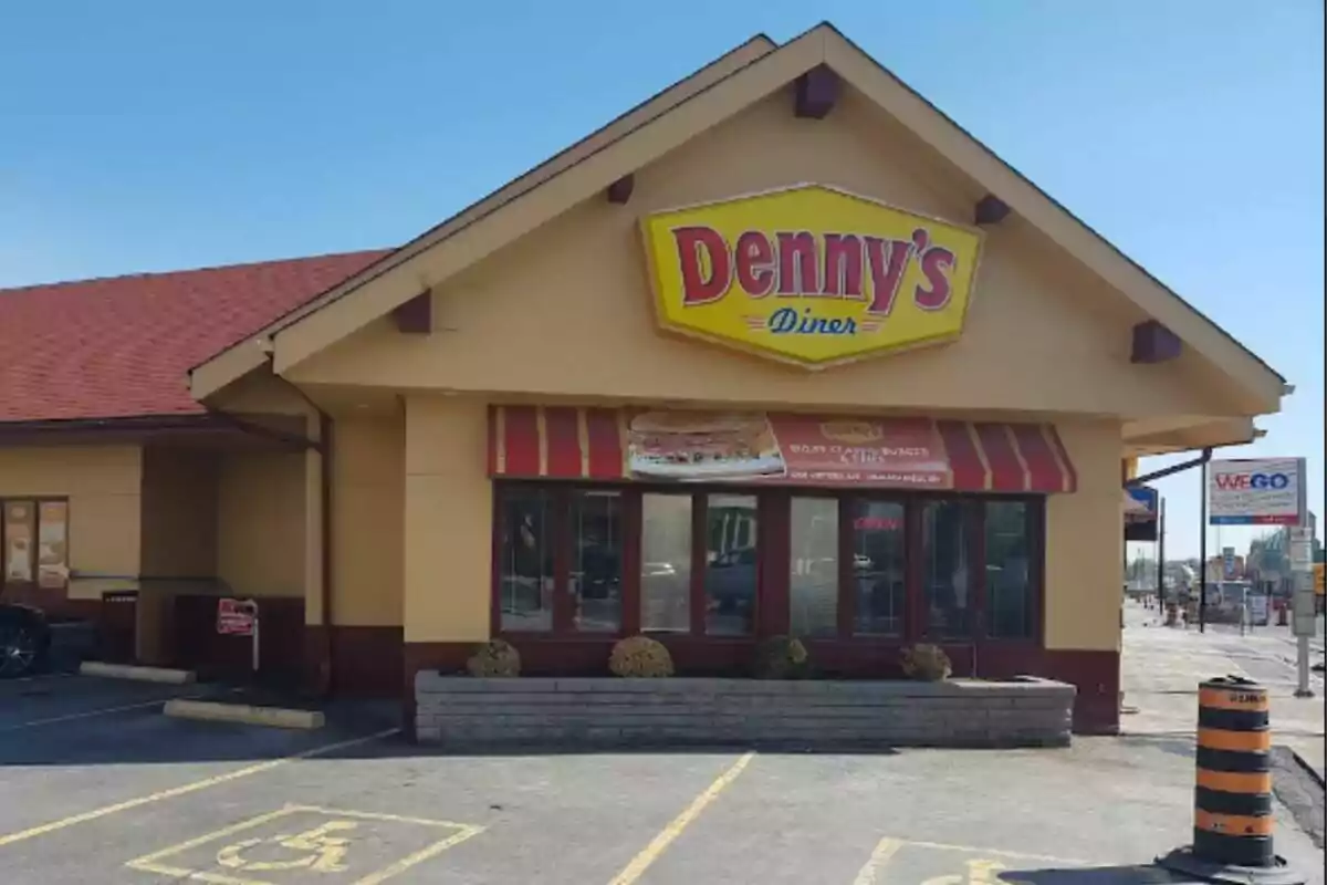 A restaurant with a yellow and red sign outside, parking in front, and a clear sky. A restaurant with a yellow and red sign outside, parking in front, and a clear sky.