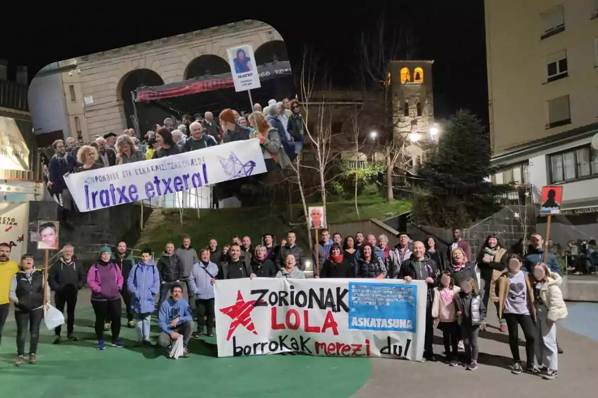 Un grupo de personas se reúne al aire libre sosteniendo pancartas y carteles en un ambiente nocturno.