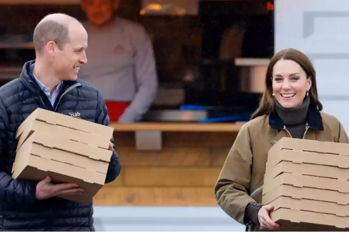 Dos personas sonrientes cargando cajas de pizza frente a un establecimiento.