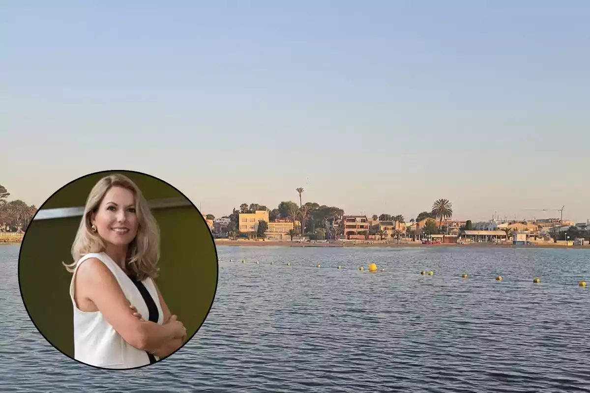 Mujer sonriendo con los brazos cruzados en un recuadro circular sobre una imagen de un paisaje costero con casas y árboles al fondo.