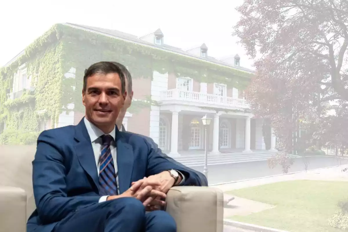 Hombre con traje azul sentado frente a un edificio cubierto de enredaderas.