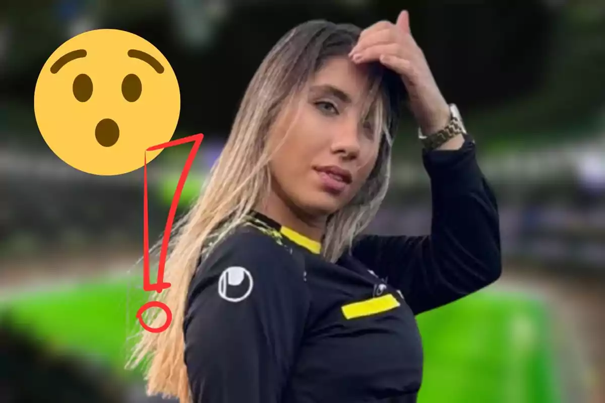 Una mujer con cabello largo y rubio viste una camiseta negra con detalles amarillos mientras se toca el cabello con una mano. A su lado hay un emoji sorprendido y un signo de exclamación rojo.