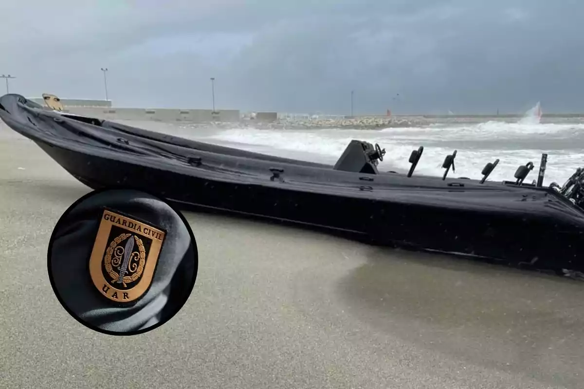 Una lancha negra varada en la playa con un emblema de la Guardia Civil en primer plano.