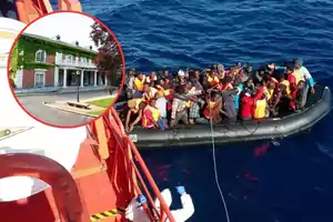 Una embarcación llena de personas con chalecos salvavidas en el mar junto a un barco de rescate, con una imagen insertada de una casa grande rodeada de vegetación.