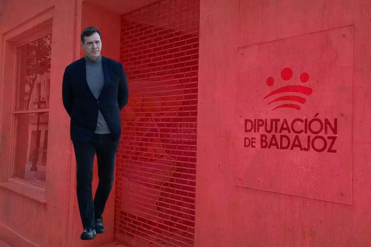 Un hombre caminando frente a un edificio con el logotipo de la Diputación de Badajoz en la pared. Un hombre caminando frente a un edificio con el logotipo de la Diputación de Badajoz en la pared.