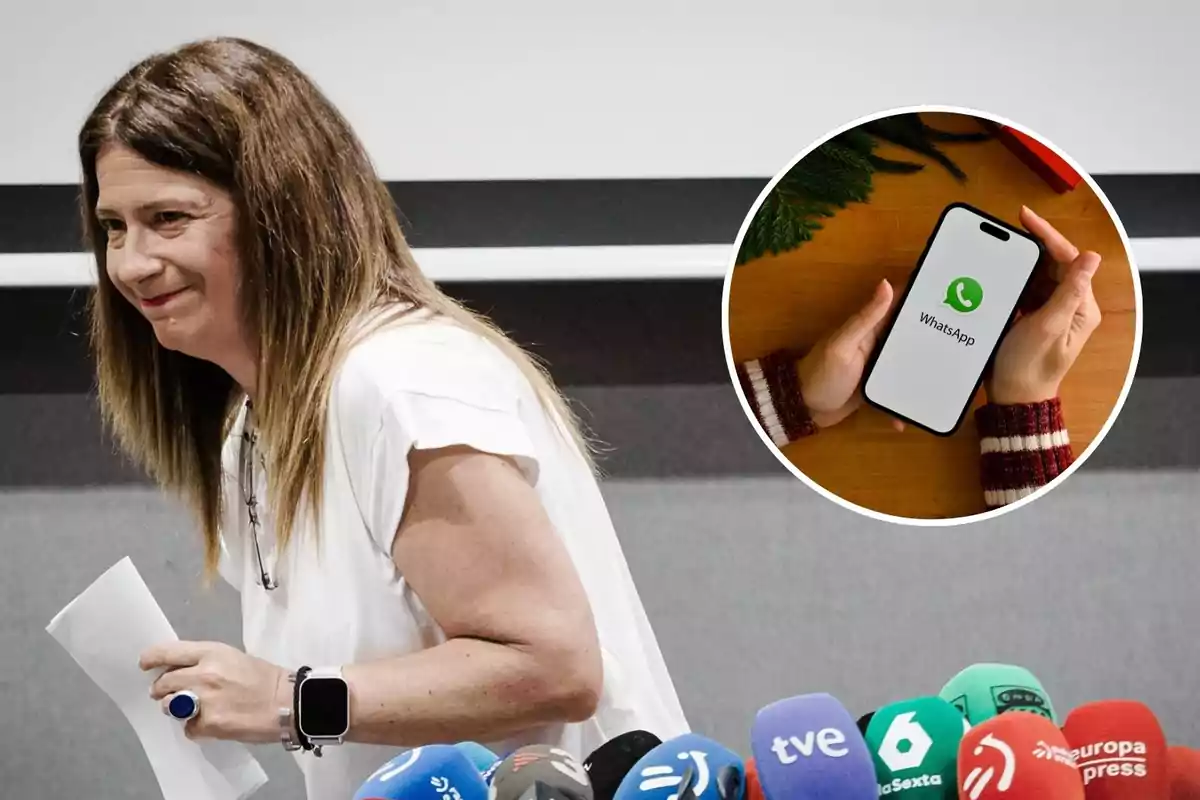 Mujer sonriente con papeles en la mano frente a varios micrófonos de medios de comunicación y un recuadro que muestra un teléfono móvil con la aplicación de WhatsApp en la pantalla.