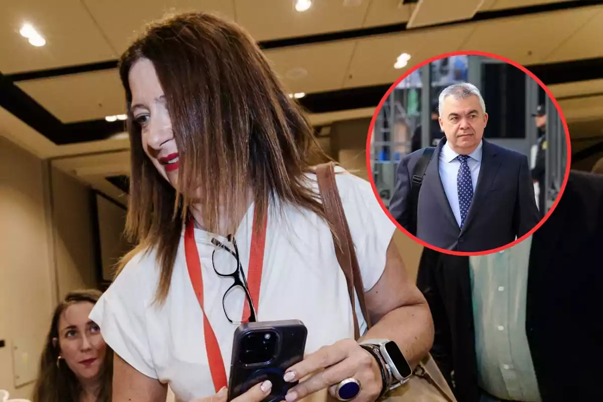 Una mujer sonriente sostiene un teléfono móvil mientras lleva gafas colgadas y una acreditación roja, al fondo se observa a otra mujer y en la esquina superior derecha aparece la imagen de un hombre de traje dentro de un círculo rojo.