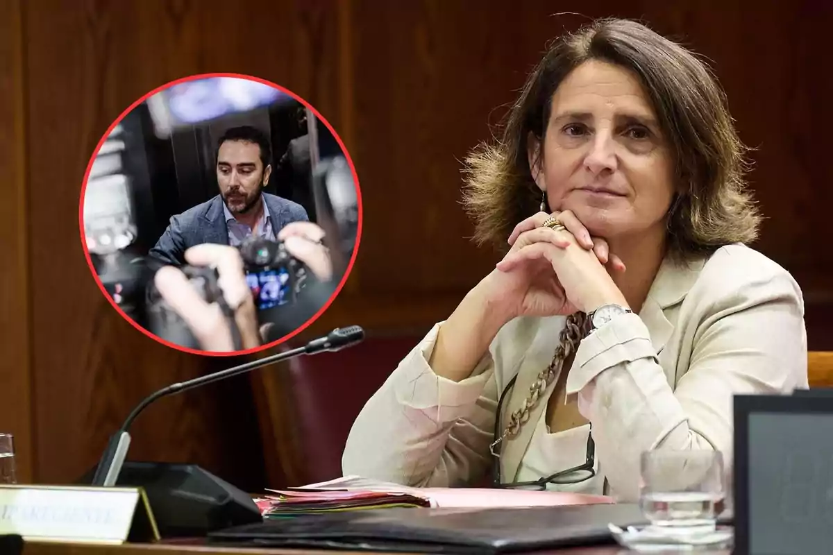 Mujer sentada en una mesa de reuniones con las manos entrelazadas y expresión seria, en la esquina superior izquierda aparece un recuadro circular con la imagen de un hombre rodeado de cámaras y micrófonos