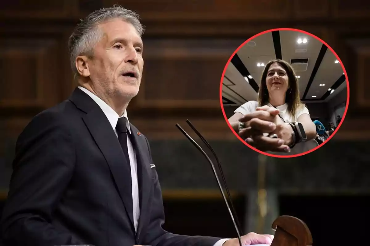 Hombre de cabello canoso y traje oscuro hablando en un podio con un micrófono, con un círculo rojo que muestra a una mujer de cabello castaño claro y camiseta blanca sentada con las manos entrelazadas en un ambiente interior iluminado.