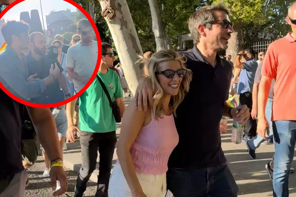 Una pareja sonriente camina abrazada en un evento al aire libre, rodeada de otras personas, mientras en un círculo rojo se destaca a un grupo de personas siendo entrevistadas.