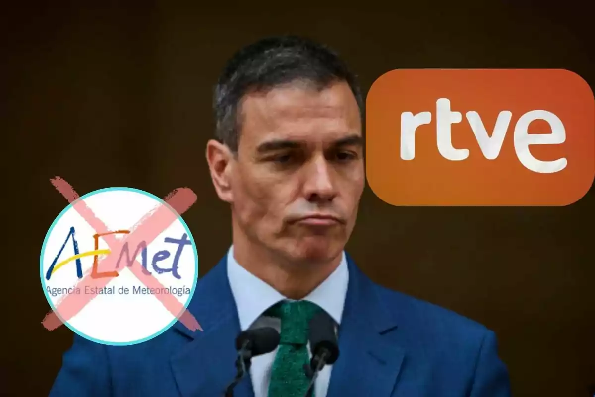 Un hombre con expresión seria en un traje azul con un micrófono frente a él y los logotipos de AEMET tachado y RTVE en el fondo.