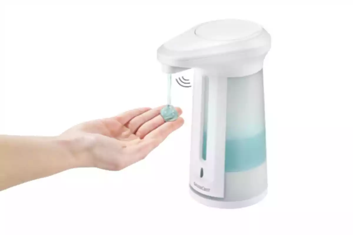 Una mano recibiendo jabón líquido de un dispensador automático blanco con sensor Una mano recibiendo jabón líquido de un dispensador automático blanco con sensor