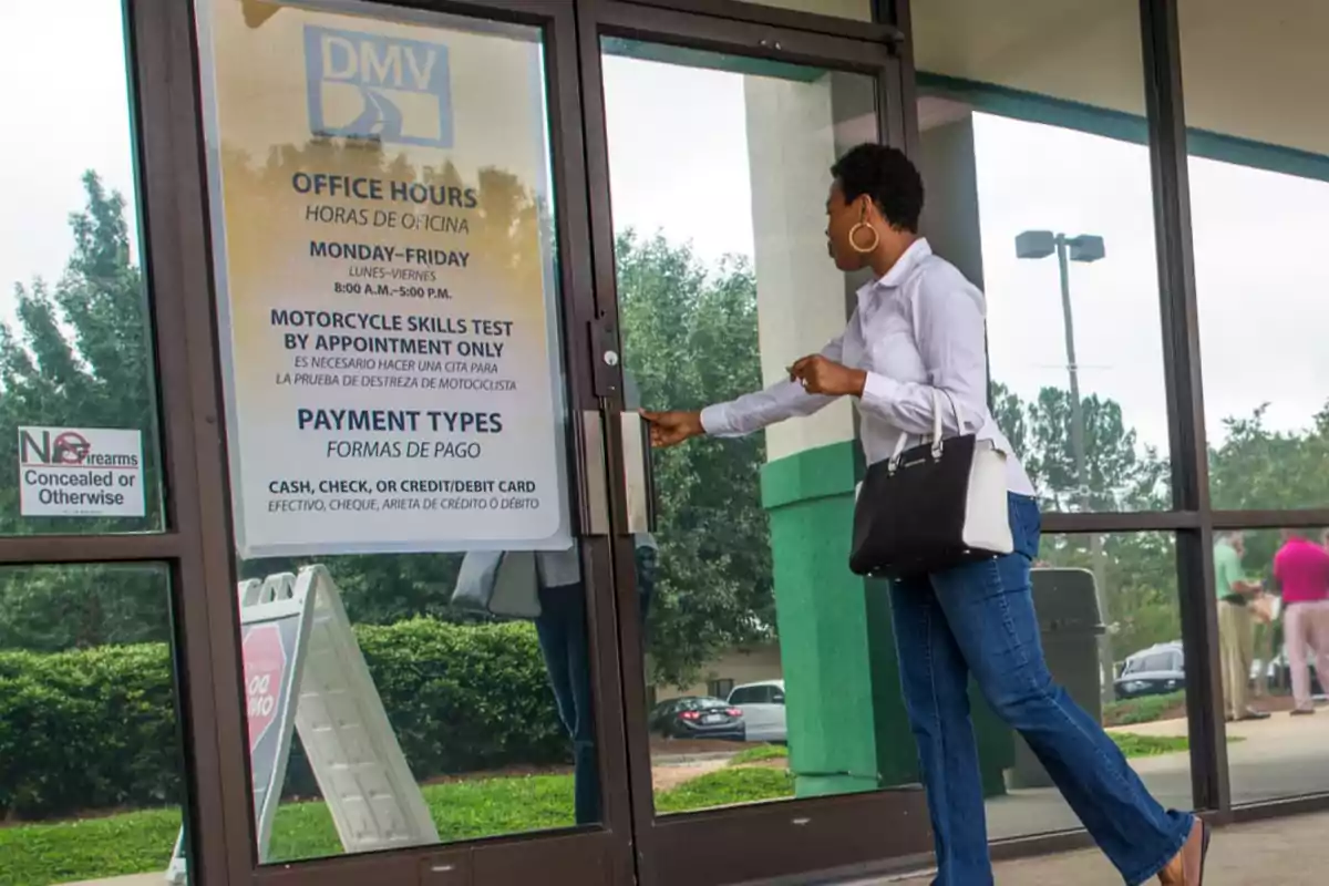 Woman opening the door of a DMV office with a sign displaying hours and payment methods at the entrance