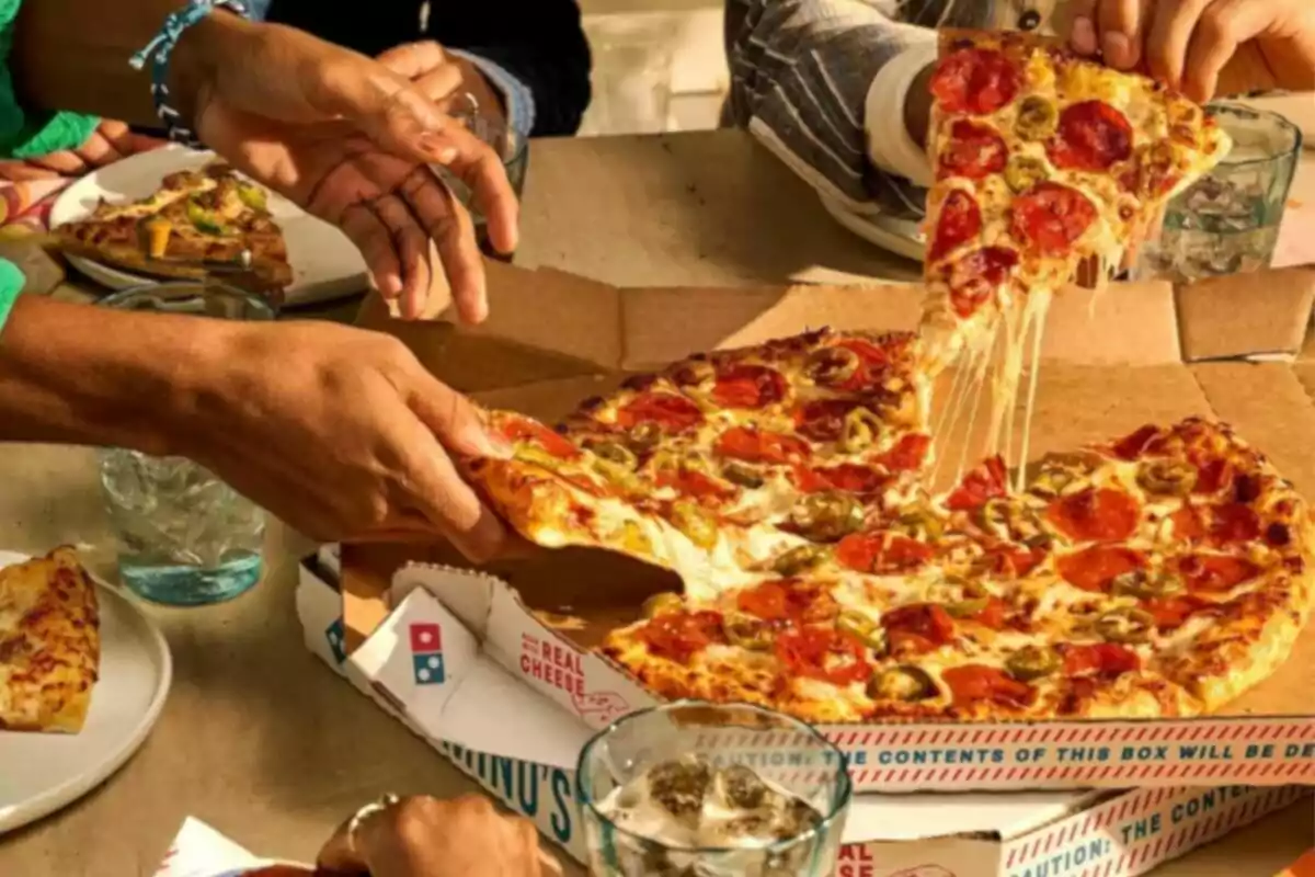 Several people sharing a pepperoni and jalapeño pizza at a table Several people sharing a pepperoni and jalapeño pizza at a table