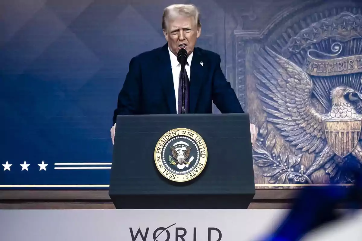 Un hombre de traje oscuro habla desde un podio con el sello presidencial de Estados Unidos, con un fondo azul y un emblema de águila.