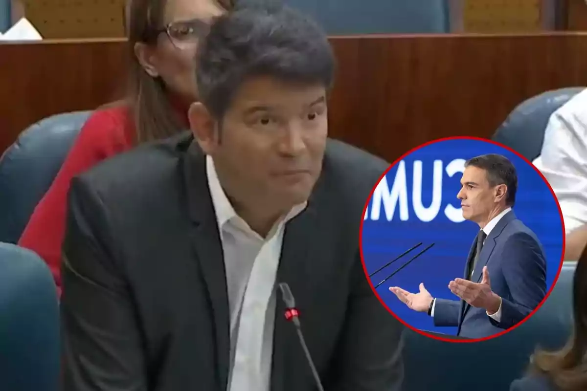 Un hombre de traje oscuro y camisa blanca está hablando en un micrófono en una sala de conferencias, con una imagen circular de otro hombre en traje azul hablando en un podio superpuesta en la esquina inferior derecha.