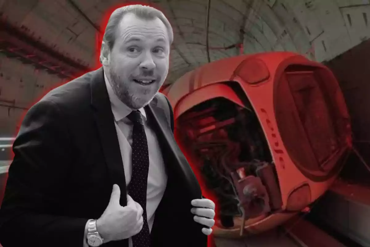 Un hombre con traje sonríe frente a un tren volcado en un túnel iluminado con luces rojas.