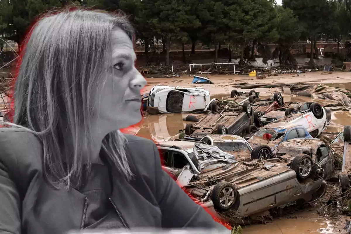 Una mujer en primer plano en blanco y negro con un fondo de autos volcados y dañados en un área inundada.