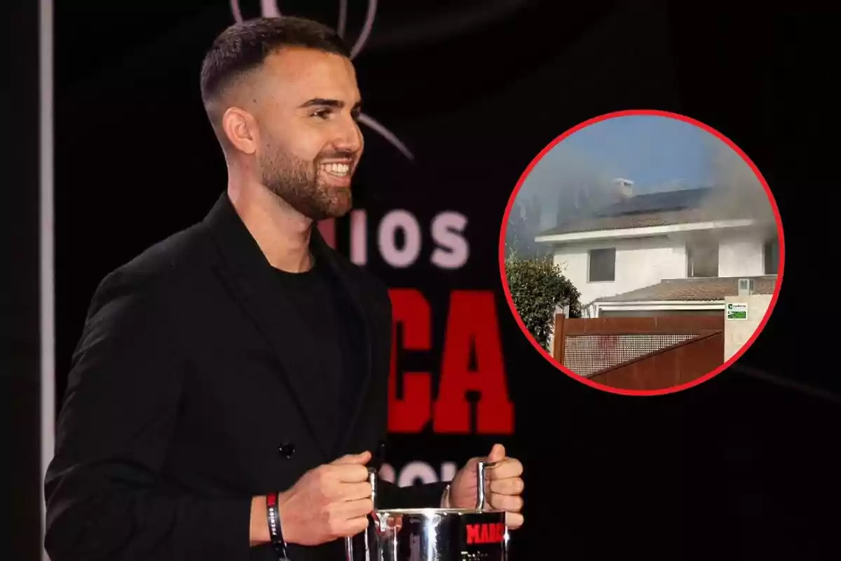 Un hombre sonriente sostiene un trofeo en un evento mientras en un recuadro se muestra una casa con humo saliendo del techo.