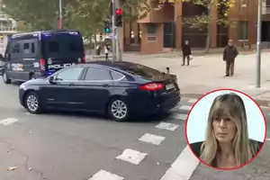 Un coche negro y una furgoneta de policía en una intersección urbana con un semáforo en rojo y un recuadro que muestra a una mujer.