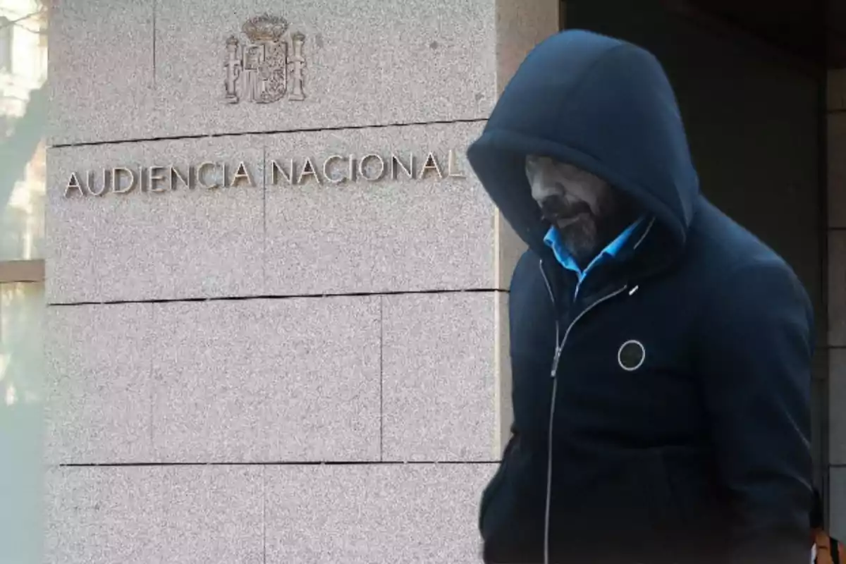 Un hombre con capucha camina frente a un edificio con el letrero "Audiencia Nacional".