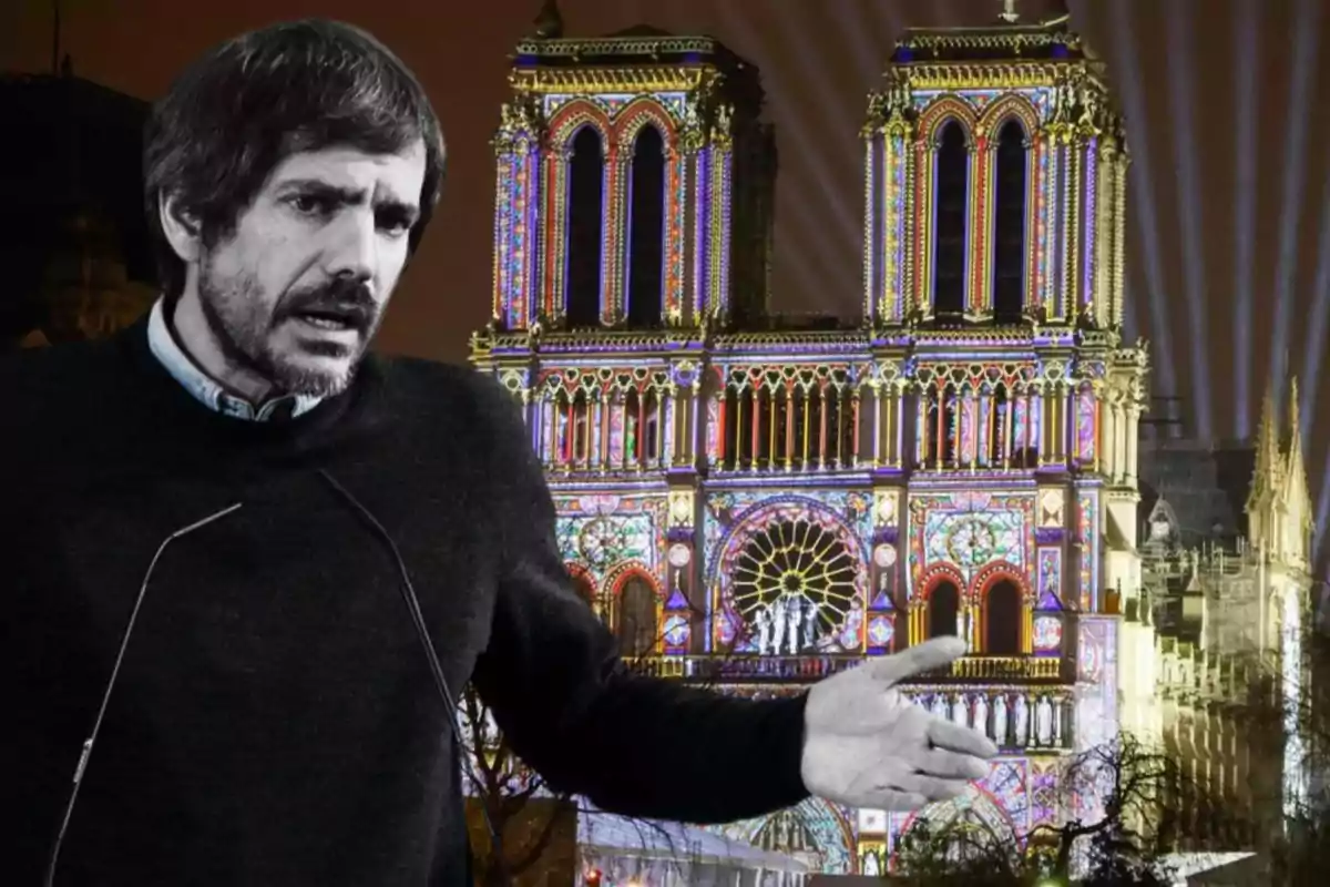 Un hombre gesticulando frente a la catedral de Notre Dame iluminada por la noche.