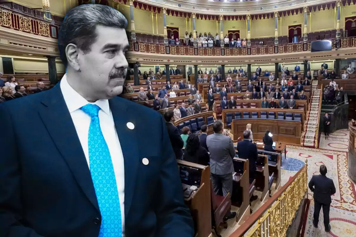 Un hombre con traje y corbata azul aparece en primer plano mientras en el fondo se observa un parlamento lleno de personas.