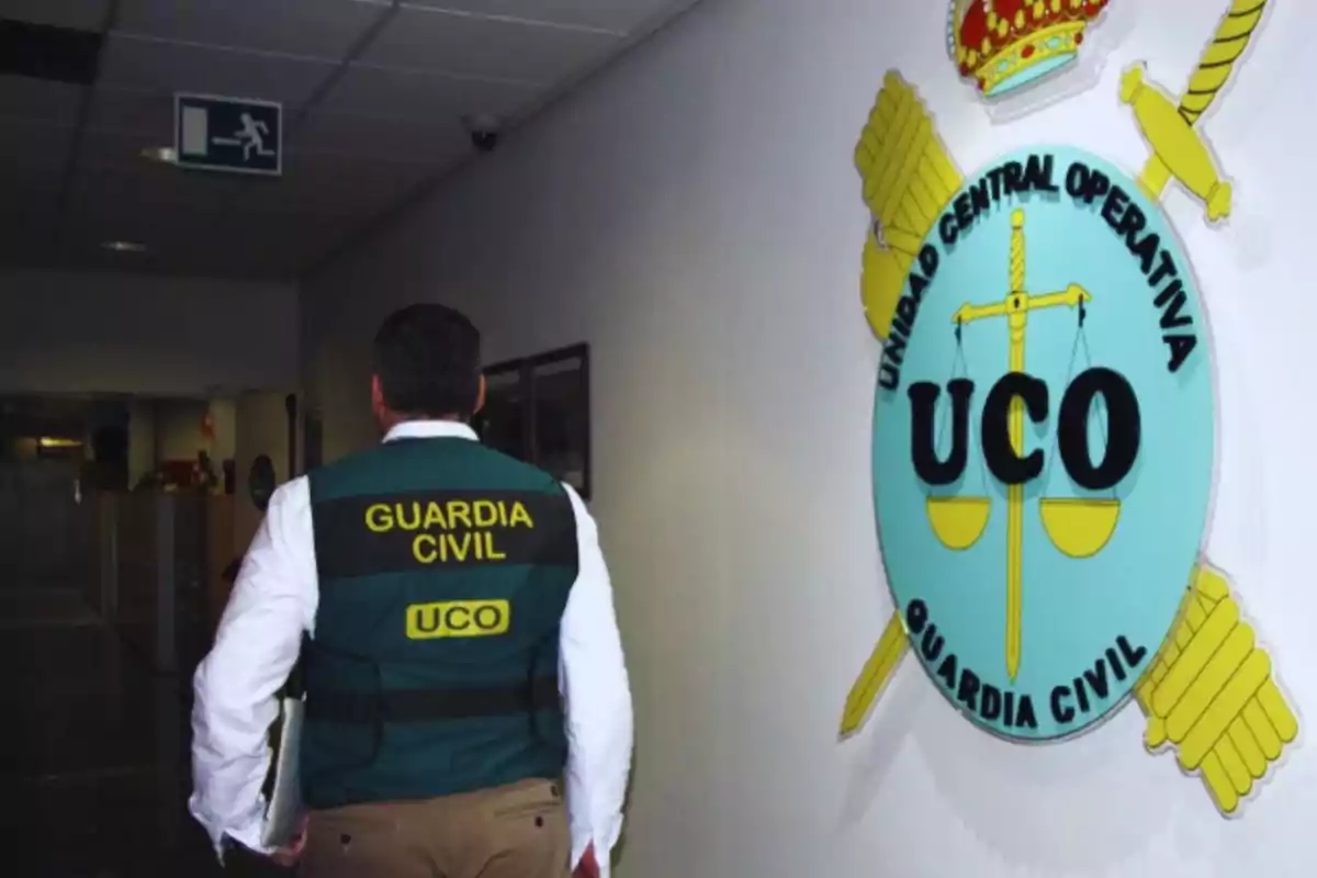 Un agente de la Guardia Civil camina por un pasillo junto a un emblema de la Unidad Central Operativa en la pared.