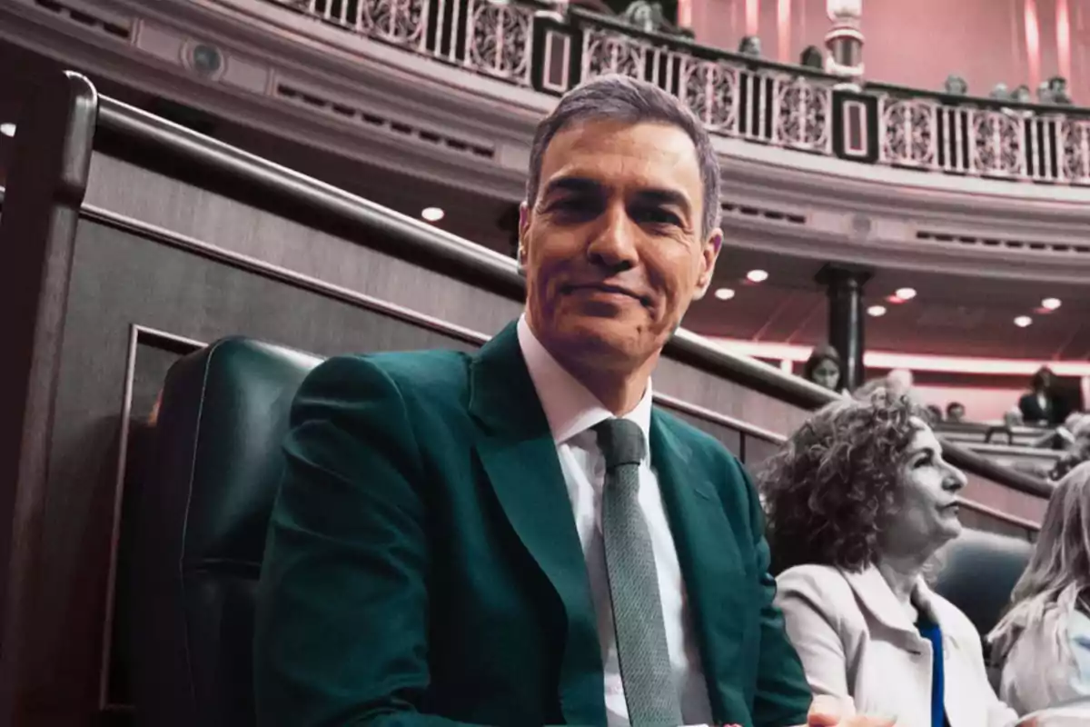 Hombre de traje sentado en un recinto parlamentario con otras personas al fondo