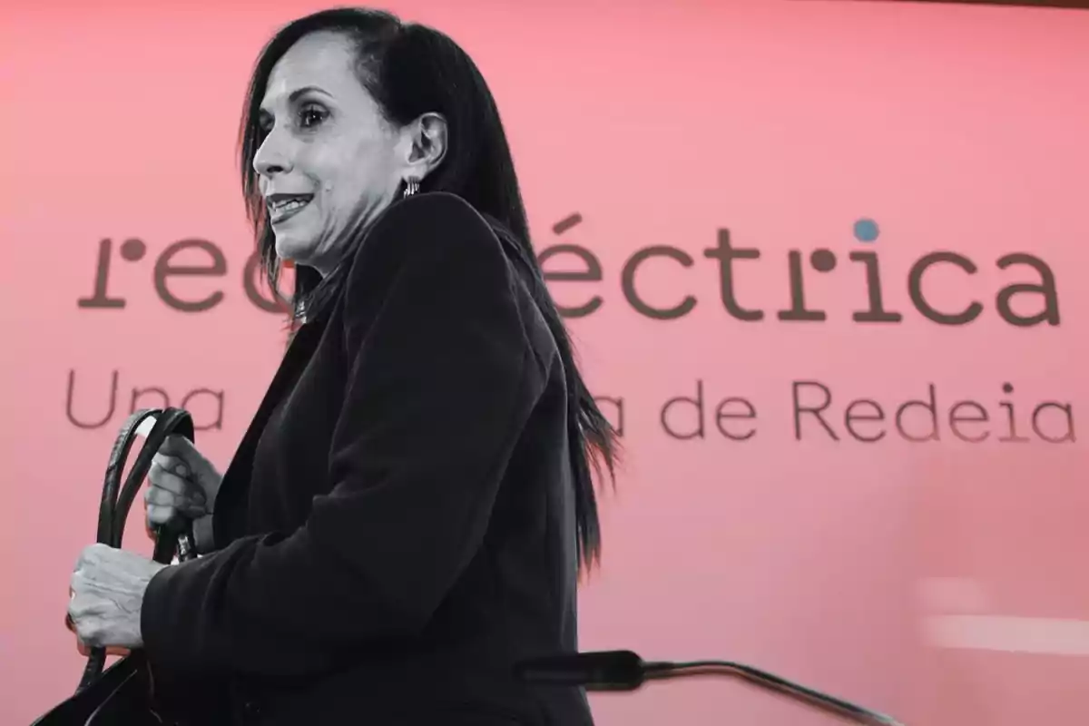 Mujer de cabello oscuro con saco negro sosteniendo un bolso frente a un fondo rosa con el texto red eléctrica