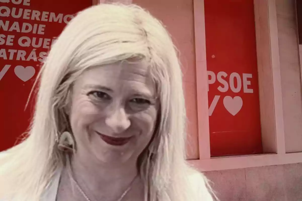 Mujer rubia sonriendo frente a una pared con carteles rojos del PSOE y corazones blancos