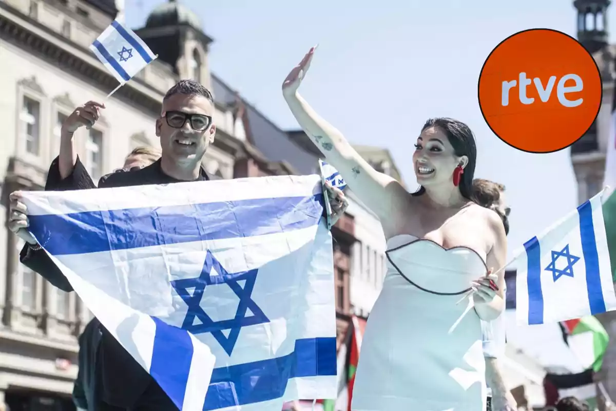 Personas sosteniendo banderas de Israel en un evento al aire libre con un logotipo de RTVE en la esquina. Personas sosteniendo banderas de Israel en un evento al aire libre con un logotipo de RTVE en la esquina.