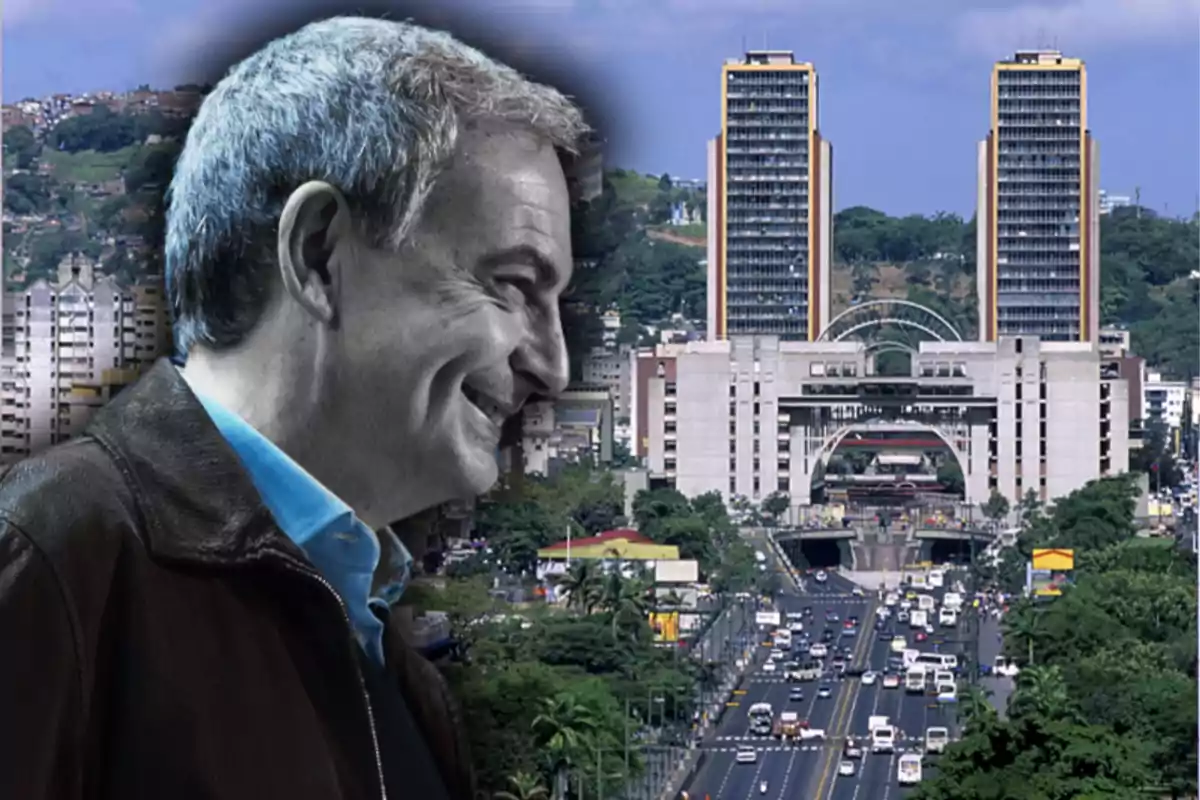 A smiling man with gray hair in front of a cityscape with tall buildings and a busy road.