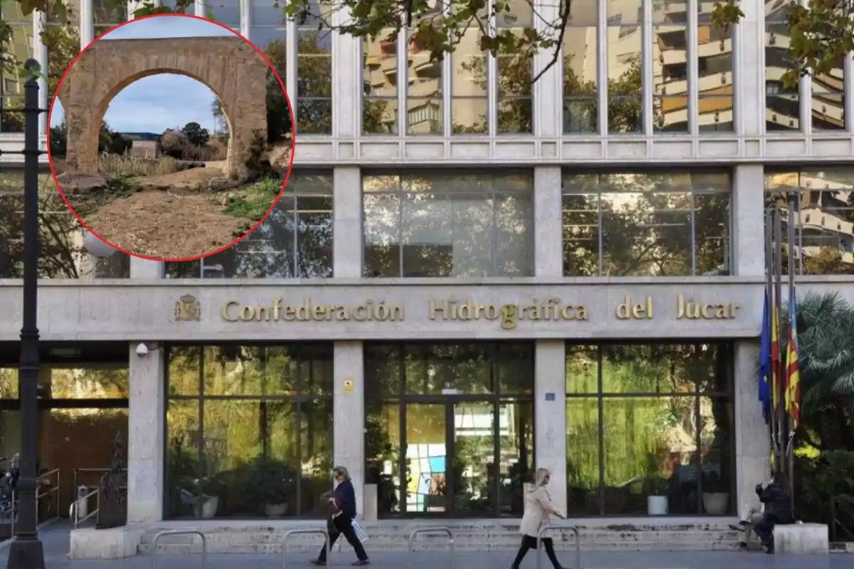 Edificio de la Confederación Hidrográfica del Júcar con un recuadro que muestra un arco de piedra en un entorno rural.