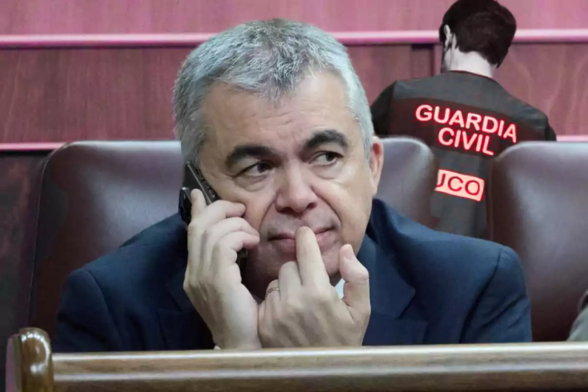 Hombre de cabello canoso hablando por teléfono con gesto pensativo mientras al fondo se ve a un agente de la Guardia Civil de espaldas.