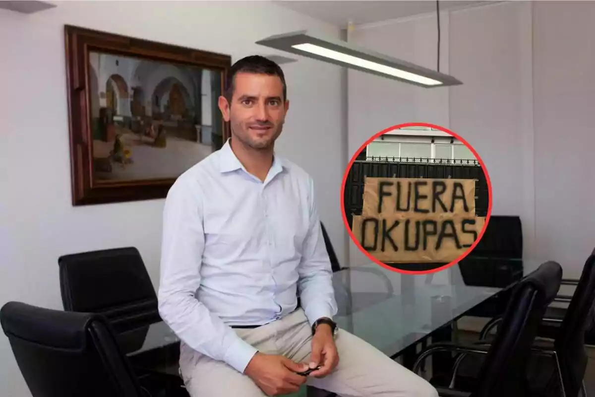 Un hombre sentado en una mesa de oficina con un cartel en la esquina que dice "Fuera Okupas".