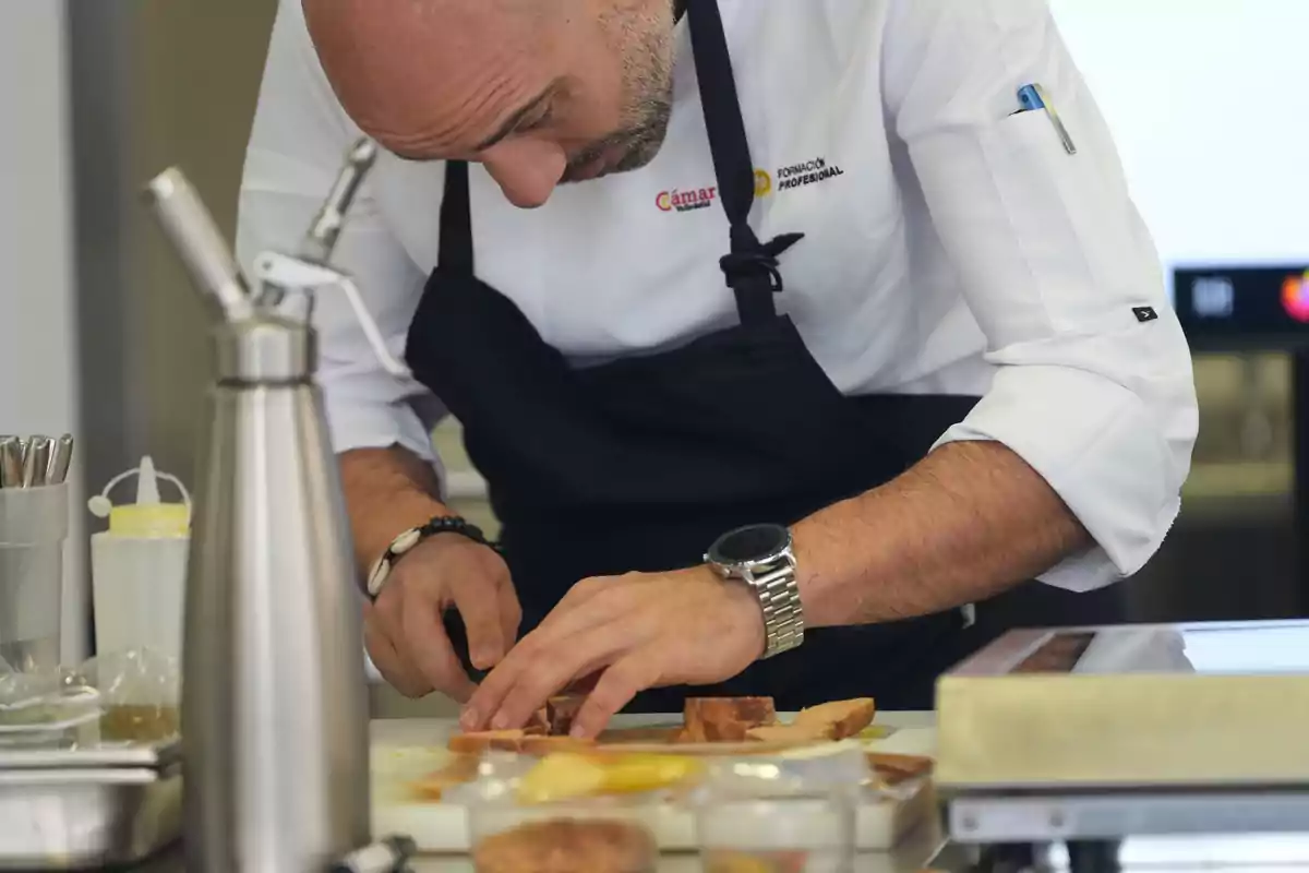 Un chef concentrado corta ingredientes en una cocina profesional.