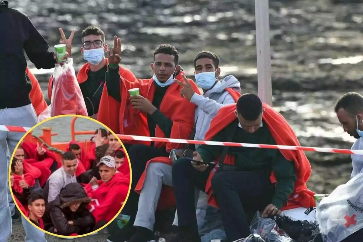 Un grupo de personas, algunas con mascarillas, están sentadas y cubiertas con mantas rojas, mientras una de ellas hace un gesto de paz con la mano y otra revisa su teléfono móvil; en la esquina inferior izquierda hay un recuadro con una imagen de más personas también cubiertas con mantas rojas.