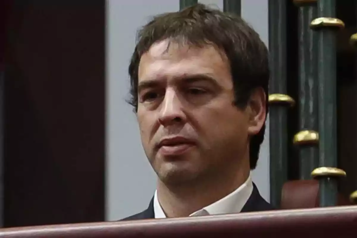 Hombre con expresión seria en un entorno formal.