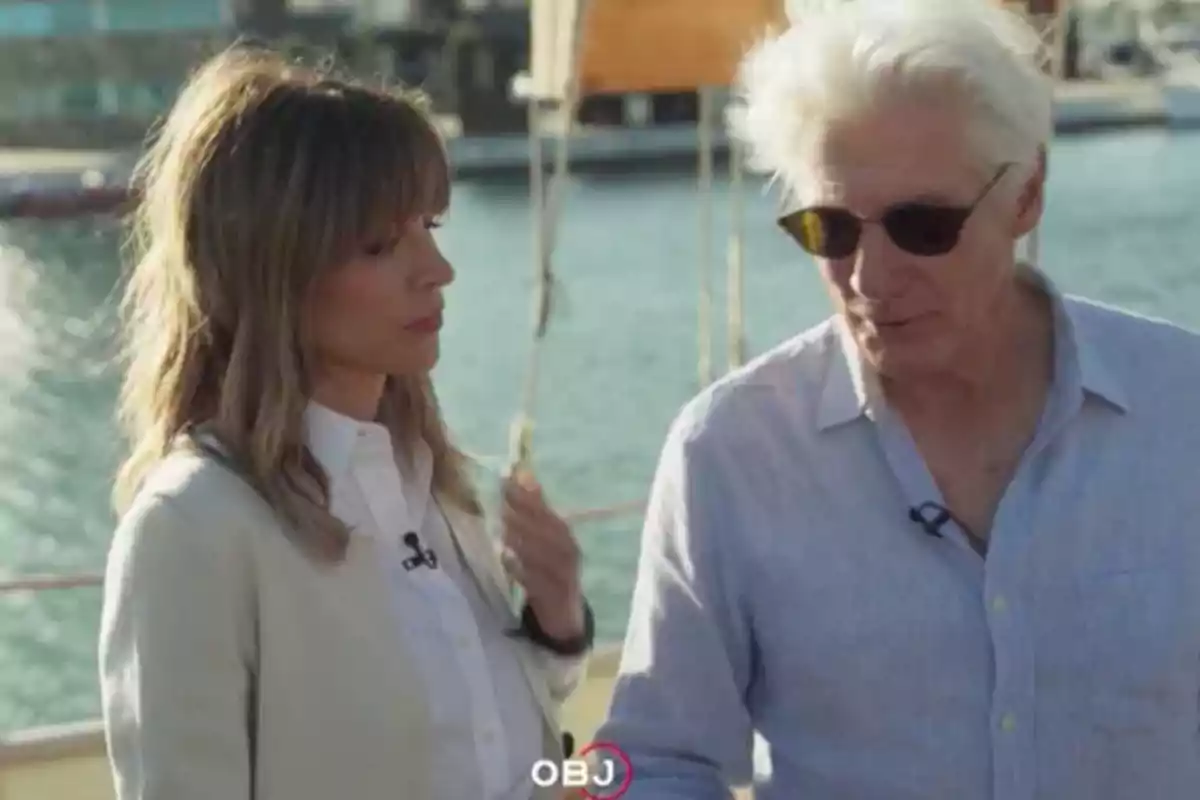 Alejandra Silva and Richard Gere talk outdoors near a body of water. Screenshot from 'El Objetivo'. Alejandra Silva and Richard Gere talk outdoors near a body of water. Screenshot from 'El Objetivo'.