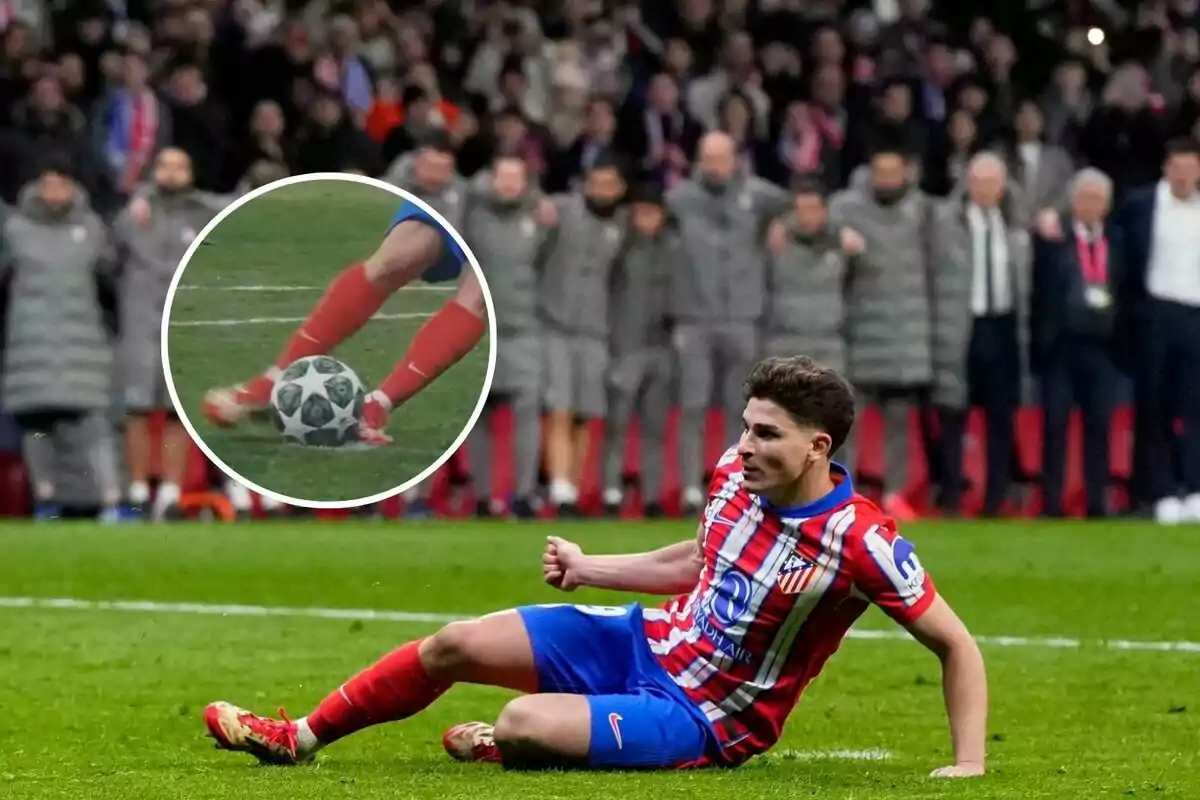 Un jugador de fútbol del Atlético de Madrid se desliza en el campo mientras un grupo de personas observa desde el fondo.