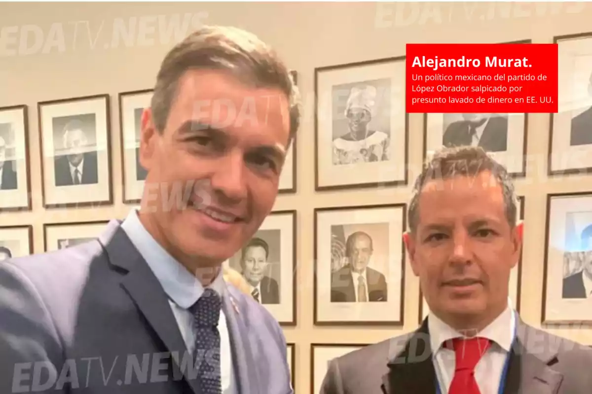 Dos hombres posan para una foto frente a una pared con retratos enmarcados.