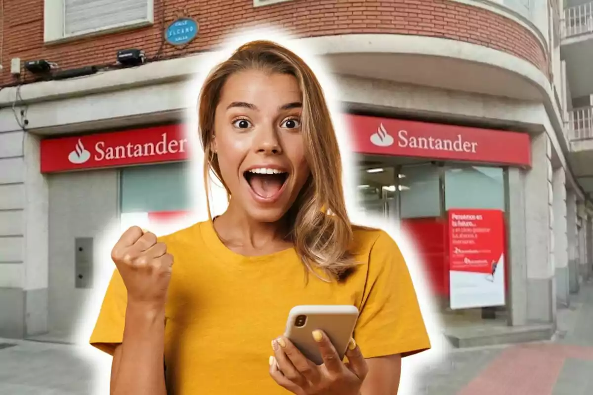 Una mujer emocionada con un teléfono móvil frente a una sucursal del banco Santander.