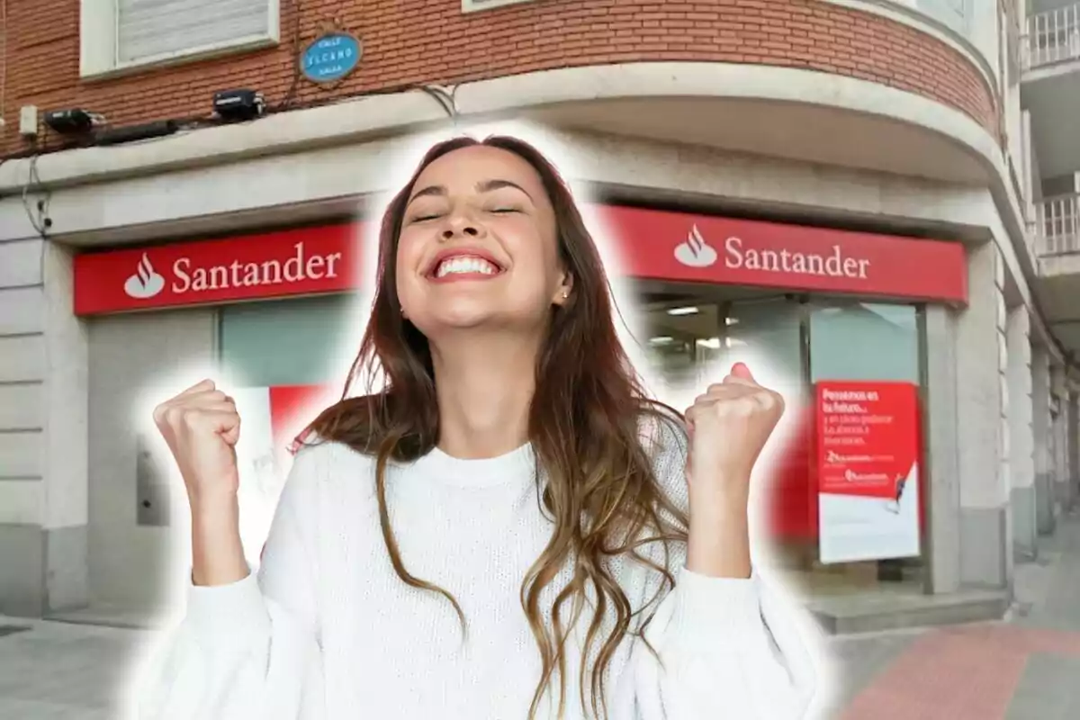 Una mujer sonriente y feliz frente a una sucursal del banco Santander.