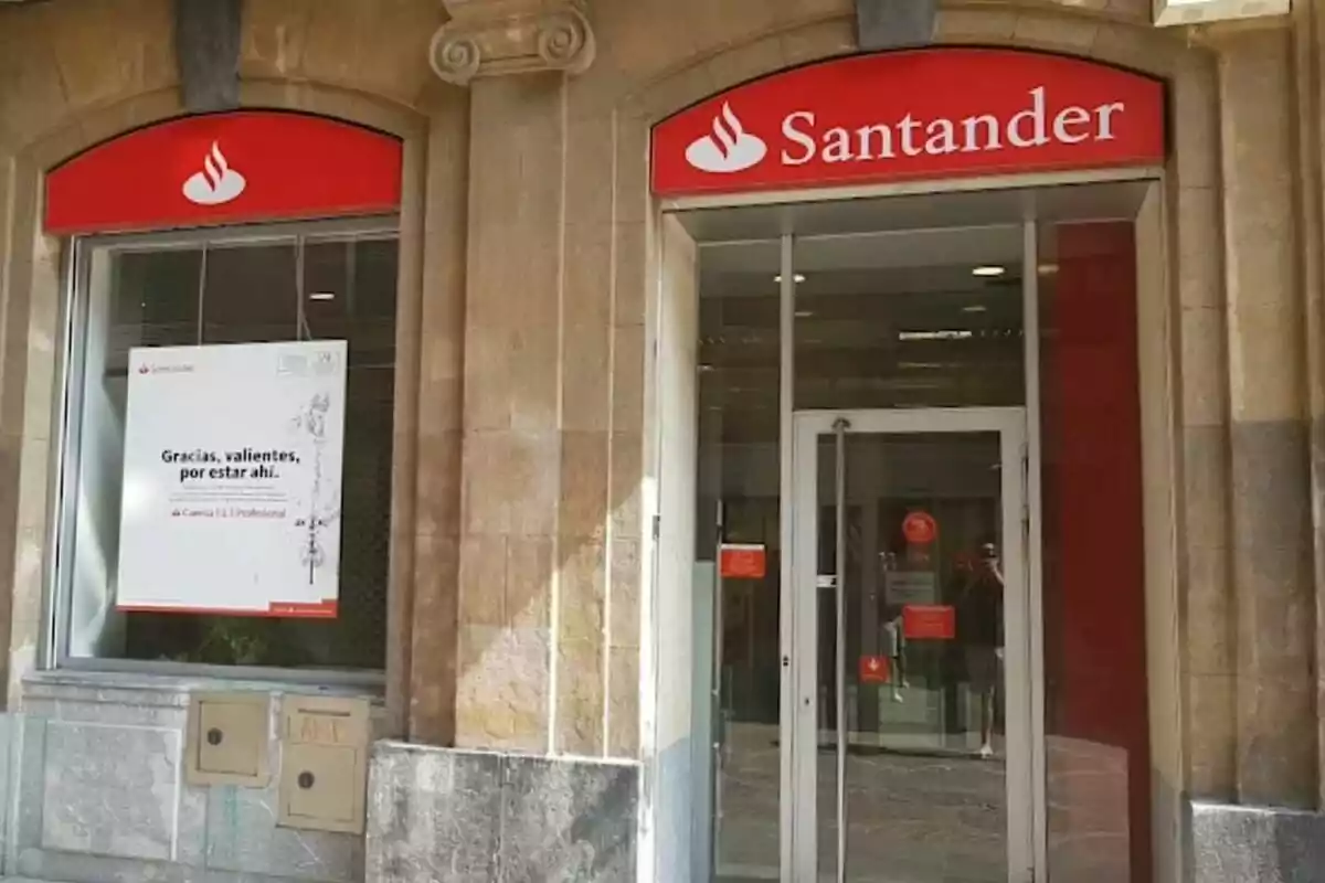 Fachada de una sucursal del banco Santander con un cartel en la ventana que dice Fachada de una sucursal del banco Santander con un cartel en la ventana que dice