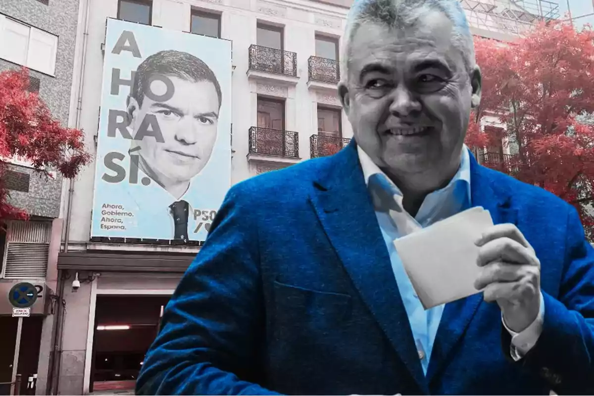 Un hombre sonríe mientras sostiene un papel, con un cartel político de fondo en una calle con árboles de hojas rojas.