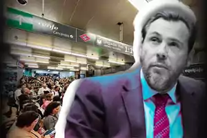 Una multitud de personas espera en una estación de tren con un cartel de Renfe Cercanías y Metro, mientras un hombre con traje y corbata aparece en primer plano.