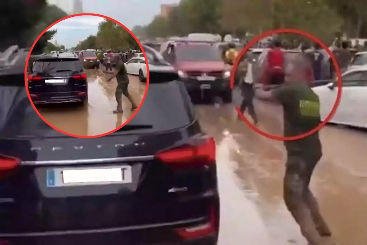 Un hombre con uniforme apunta con un arma en una calle llena de coches y personas, mientras el suelo está cubierto de barro.