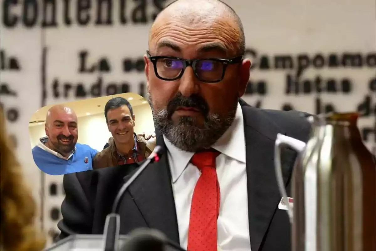 Un hombre con gafas y barba está sentado frente a un micrófono, vistiendo un traje oscuro y corbata roja, con una imagen superpuesta de dos personas sonriendo.