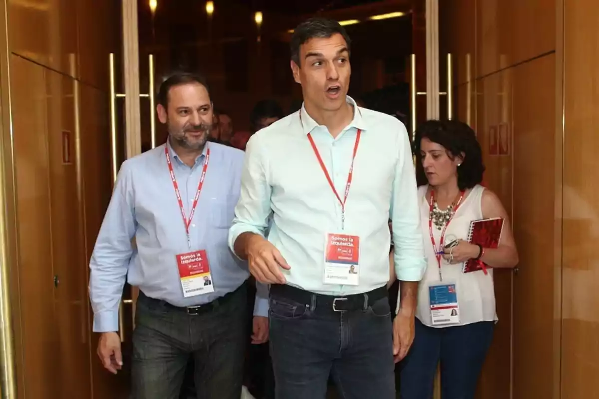 Un grupo de personas con credenciales colgadas del cuello camina por un pasillo iluminado.